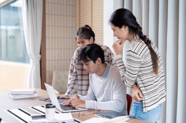 Sınıf ortamında bir dizüstü bilgisayar üzerinde dikkatlice işbirliği yapan odaklanmış bir grup öğrenci, grup çalışması ve takım çalışmasını vurguladı.