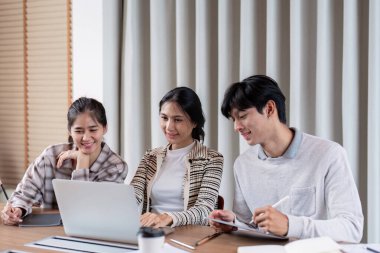 Grup çalışması için bir dizüstü bilgisayarı paylaşan işbirlikçi öğrenciler, takım çalışmasının ve kolektif akademik ilerlemenin önemini vurguluyorlar.