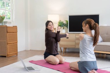 Mutlu lezbiyen çift sıcak oturma odalarında birlikte egzersiz yapmaktan zevk alıyor, paylaşılan spor ve keyfi vurguluyorlar..