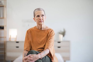 Modern bir oturma odasındaki koltukta oturan düşünceli, yaşlı bir kadın hayat tecrübelerini yansıtıyor..