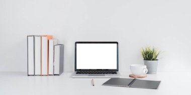 Boş ekranı, kitapları ve verimliliği destekleyen bir bitkiyi barındıran minimalist bir çalışma alanı..