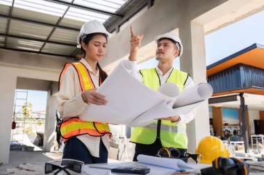 Bir inşaat alanının planlarını tartışan mühendisler, proje planlama ve yürütme üzerine odaklanıyorlar.