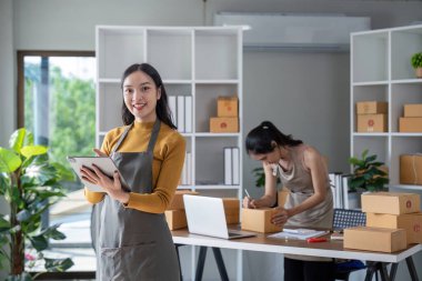 Kadınlar e-ticaret ambalaj görevlerini yönetmek için dijital araçlar kullanıyor, modern ofis ortamında verimlilik ve doğruluğa odaklanıyor.