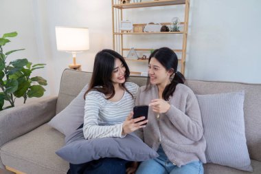 Bir lezbiyen çift akıllı telefondaki içerik üzerine bağ kuruyor. Oturma odasındaki kanepede dinlenirken gülüşlerini ve bağlantılarını paylaşıyorlar..