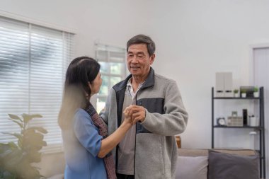 Yaşlı bir çift oturma odalarında sevgi dolu bir anı ve birlikteliği gösteren şefkatli bir dansı paylaşıyor..