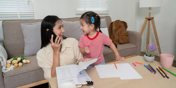 stock image Mother balancing work with her daughter by her side, reflecting modern parenting and multitasking in a comfortable home environment.