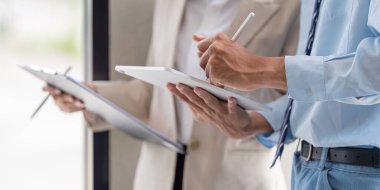 İş dünyasından profesyonellerin elleri, modern ve verimli işbirliğini resmeden bir toplantı sırasında tablet ve belgelerle aktif olarak ilgileniyorlar..