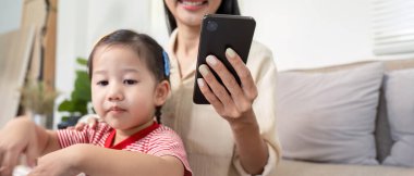 Bir anne çocuğunu akıllı telefon kullanarak uzaktan ebeveynliğe bağlar, teknolojiyi ebeveynlik dinamiğiyle harmanlar..