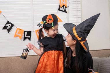 Bir anne ve kız, Cadılar Bayramı ruhunu kostümler ve dekorasyonla paylaşarak neşe ve kahkahayı paylaşır..