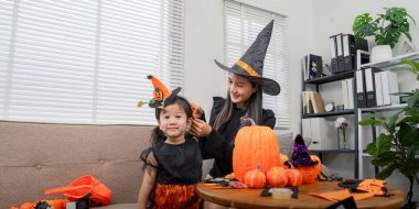 Bir anne, kızının Cadılar Bayramı 'na hazırlanmasına yardım eder. Dekoratif el sanatları, yaratıcılığı ve şenlik hazırlığını teşvik eder..