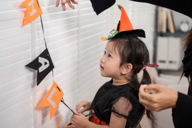 Bir çocuk Cadılar Bayramı dekorasyonunda annesine yardım etmek için can atıyor, tatil hazırlıklarının heyecanını öğreniyor..