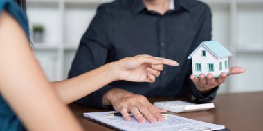 Bir müşteri ve emlak acentesi, potansiyel ev yardımları ve kısıtlamalarının anlaşılmasını kolaylaştırmak amacıyla, mülkiyet özellikleri hakkında ayrıntılı bir tartışmaya sahiptir..