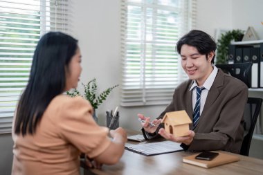Genç bir emlakçı, en iyi yatırım seçeneklerinin yararlarını vurgulayarak müşterisiyle çeşitli mülkiyet seçeneklerini büyük bir hevesle tartışır..