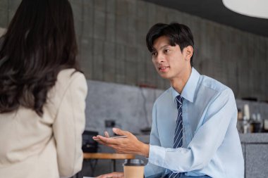 Finansal danışman, müşterisiyle samimi bir kafe ortamında stratejik planlamayı tartışır, kişisel mali tavsiyeler ve müşteri ilişkileri üzerine odaklanır..