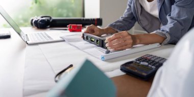 A woman engineer ensures precision on blueprint layouts using a level tool and calculator, highlighting accuracy in architectural work. clipart