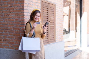 Genç bir kadın Kara Cuma online anlaşmalarına hevesle hazırlanıyor, kredi kartını ve akıllı telefonunu bir butiğin dışında tutuyor..