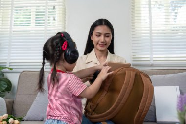 Bir anne, küçük kızının okul çantasını düzenlemesine yardım eder. Hazırlık ve dikkatli hazırlıklara odaklanır..