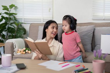 Bir anne ve kız bir ödev oturumuna katılır, bir not defterini çalışma materyalleri ve iletişim ile birlikte gözden geçirirler..