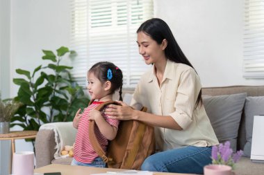 Şefkatli bir anne, kızının sırt çantasını düzenlemesine yardımcı olur ve verimli ve heyecan verici bir okul gününe hazırlanır..