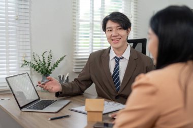 Bir emlakçı potansiyel bir alıcıyla konut olanaklarını tartışır, mülkiyet seçenekleri ve piyasa görüşlerine odaklanır.