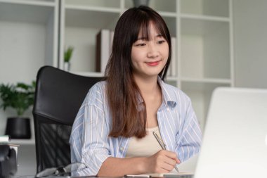 Gülümseyen bir öğrenci interaktif bir çevrimiçi sınıfta, önemli sezgileri yakalamak için notlar alıyor..