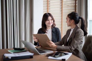 Bir kadın finans danışmanı, mali stratejileri geliştirmek için kurumsal bir toplantı çerçevesinde iş arkadaşına anahtar öngörüler sunar..