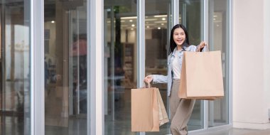 Bir moda alışverişçisi mağazadan çıkar, elinde birkaç çanta ile Kara Cuma alışveriş heyecanını ön plana çıkarır..