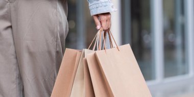 Alışveriş yapan kişi, başarılı bir alışveriş deneyimi ve tüketici katılımını gösteren birden fazla kese kağıdı taşır..