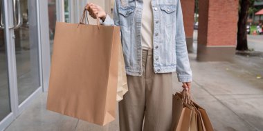 Modern bir alışverişçi, Kara Cuma alışverişleri ve perakende zaferindeki başarısını temsil eden büyük alışveriş çantalarını sergiliyor..