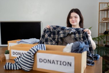 Şefkatli bir gönüllü bağış kampanyası için giysiler hazırlar, toplum hizmeti konseptini somutlaştırır ve eylem sırasında şefkat gösterir..