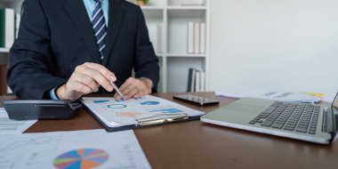 Bir muhasebeci, iş büyümesini sağlamak için dizüstü bilgisayar ve ayrıntılı analiz çizelgeleri kullanarak finansal tahminler hazırlar.