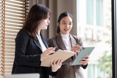 İki iş analisti tablet kullanarak dijital stratejileri tartışıyor, kurumsal bir ortamda modern işbirliği tekniklerini somutlaştırıyorlar..