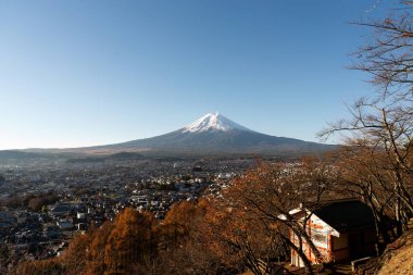 Fuji Dağı 'nın panoramik bir manzarası. Sonbahar ağaçları ve geleneksel bir tapınak çerçeveli. Japonya' nın dingin güzelliğini ve kültürel mirasını yansıtıyor..