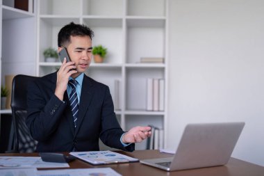 Bir iş danışmanı müşterileriyle telefonda görüşür, pazar görüşlerini ve iş büyümesi için stratejik çözümleri tartışır.