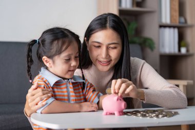 Bir anne ve çocuğu birlikte para sayarak para biriktirmenin ve maddi bağ kurmanın önemini gösteriyor..