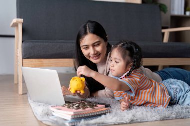 Bir ebeveyn ve çocuk, çevrimiçi mali araçların yardımıyla tasarrufları saymakla, para yönetimi becerilerini teşvik etmekle meşguldür..