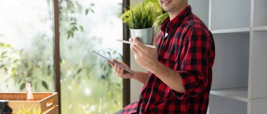 Bir dijital bahçıvan bir saksı ve tableti dengeleyerek, akıllı bahçıvanlık uygulamalarının entegrasyonunu gözler önüne seriyor.