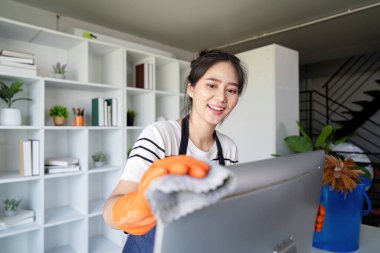 Kendini işine adamış bir temizlikçi, temizlik ve hijyenik bir çalışma ortamı sağlamak için bir ofis masasını cilalamaya odaklanır..