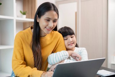 Bir anne ve kızı dizüstü bilgisayarla bağ kuruyor, eğitim faaliyetlerine ve e-öğrenime birlikte odaklanıyorlar..