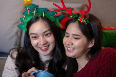 Interracial friends savor hot drinks while surrounded by festive decor, enjoying the warmth of holiday camaraderie. Concept of shared moments and seasonal warmth. clipart