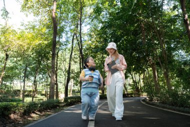 Parkta yürüyüş yapan iki arkadaş, akondroplazi üzerine yoğunlaşarak çeşitlilik ve kapsamı vurguluyorlar..