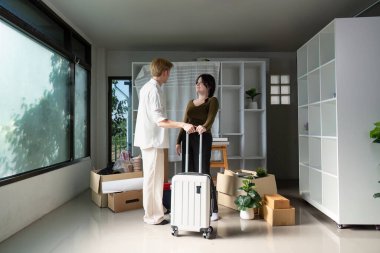 Asyalı çift, yeni evlerinde bavullarını boşaltırken yeni bir başlangıç ve arkadaşlığın önemini vurgulayarak bavullarıyla bir bağ anının keyfini çıkarıyorlar..