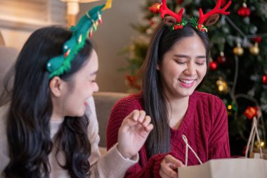 Lezbiyen partnerler, Noel ruhunun sıcaklığıyla birbirlerine hediyeler verirken gülümseme ve kahkahaları paylaşırlar..