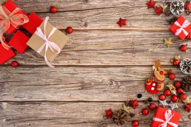 Kırmızı ve altın madalyaların, hediye kutularının ve ahşap bir masada süslerin yer aldığı neşeli bir Noel sahnesi..