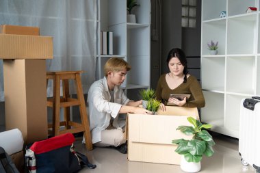 Asyalı çift bir kutudan eşyaları çıkarmaya odaklanmış, yeni yaşam alanlarını dikkatli bir yaklaşımla hazırlıyorlar..