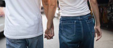 Genç Asyalı çift el ele yürüyorlar, renkli bir pazar ortamında gündelik bir anın tadını çıkarıyorlar, sevgilerini sergiliyorlar..