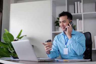 Modern ofis ortamında kahve içerken konferans sırasında birden fazla iş yapan bir iş adamı..