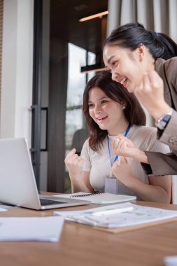 İki meslektaş, modern bir ofiste bir proje üzerinde çalışırken önemli bir iş dönüm noktasını kutladılar.