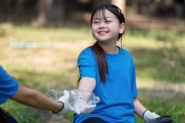 Genç bir kız, aile temizliği, takım çalışması ve çevre bakımı gibi etkinliklere neşe içinde katılıyor..