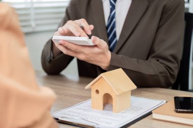 Profesyonel biri, bir ofiste iş birliği ve planlama sergileyen bir müşteriyle gayrimenkul stratejilerini tartışır..